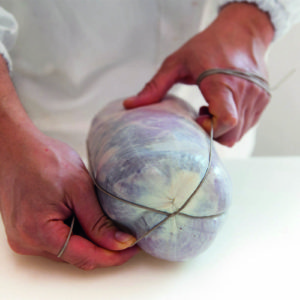 Fase di legatura manuale dei salumi: sapienza artigianale e rispetto della tradizione norcina nella lavorazione dei prodotti – Felino Parma